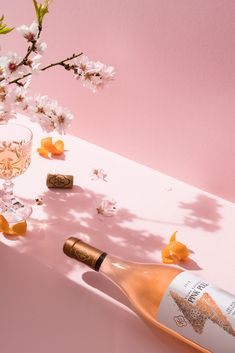 a bottle of champagne next to a glass with some flowers on it and two corks