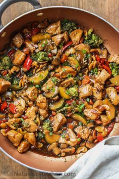 chicken, broccoli and peppers in a skillet on a wooden counter top