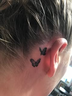 a woman's behind the ear tattoo of two butterflies