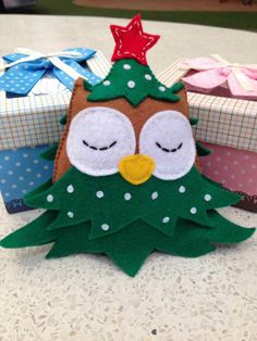 an owl sitting on top of a table next to two wrapped gift boxes with eyes closed