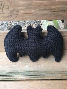 a crocheted black bear sitting on top of a wooden bench