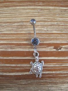 This super cute belly button ring features a silver  turtle charm that hangs from a standard 14 gauge surgical steel barbell with a double light purple gem. It measures 1 inch long. Thanks for taking a look!   *If you would like this belly button ring in a different color gem or stone, just let me know. I would love to make it for you!* Belly Button Jewelry, Purple Gems, Turtle Charm, Belly Button Ring, Button Ring, Button Jewelry, Colored Gems, Blue Gems, Hamsa Hand