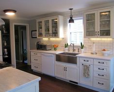 a kitchen with white cabinets and wooden floors