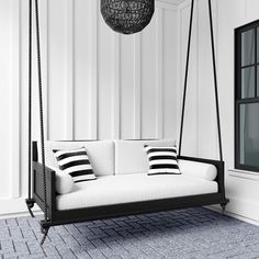 a black and white photo of a swing bed in a room with striped pillows on it