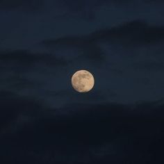 the full moon is seen through dark clouds