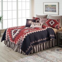 a bed with red, white and blue bedspread in a room next to a window