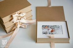 an open box with a ribbon around it next to a small photo in a box