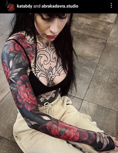 a woman with tattoos sitting on the ground