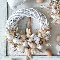 an easter wreath with eggs and flowers on a white wooden surface next to other decorations