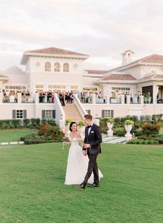 a bride and groom walking in front of a large white building with steps leading up to it