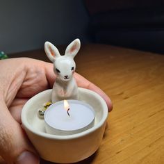 a small white rabbit sitting in a tea light holder