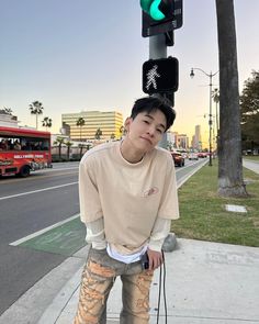 a young man standing on the sidewalk next to a traffic light