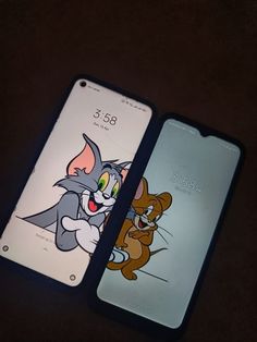 two cell phones sitting next to each other on top of a black surface with cartoon characters painted on them