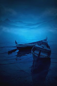 two boats sitting in the water at night