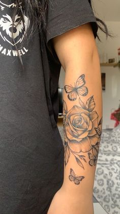 a woman's arm with a rose and butterflies tattoo on it