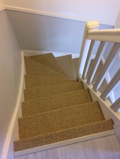 a stair case with carpeted steps leading up to the top floor and bottom handrail