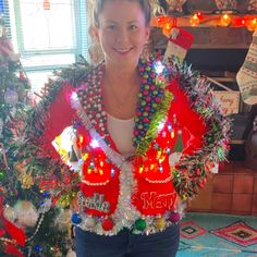 a woman standing in front of a christmas tree with decorations on her chest and arms