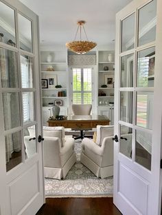 an open door leading to a living room with two chairs and a table in it