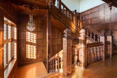 an ornate wooden staircase with chandelier and windows