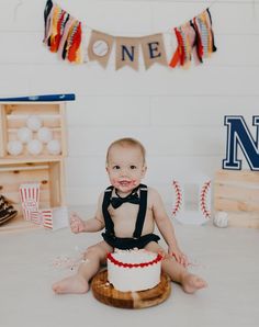 a baby sitting on the floor in front of a cake