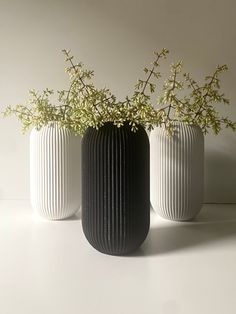 three white and black vases with flowers in them