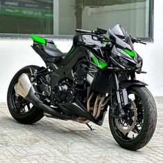 a green and black motorcycle parked in front of a building