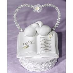 an open book shaped like a heart with two doves on top and pearls in the middle