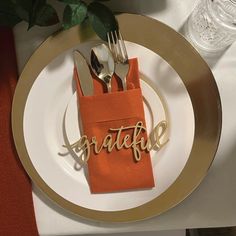 a place setting with orange napkins and silverware