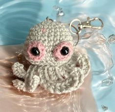 a crocheted keychain with an octopus on it's side sitting in water