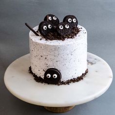 a cake decorated with oreo cookies and eyes on a marble plate, ready to be eaten