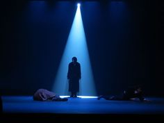 a man standing in the middle of a stage with two people laying on the ground