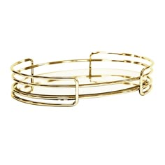 three bang bracelets with gold colored metal wire and clear glass, set on a white background