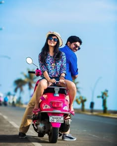 a man and woman riding on the back of a pink scooter