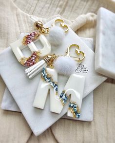 three white and gold earrings on top of a napkin next to a cell phone charger