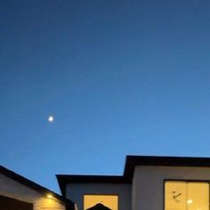 an airplane is flying in the sky over some houses at night time with lights on