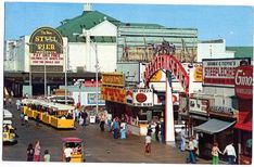 an old photo of people walking around in front of stores and restaurants on the boardwalk