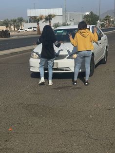 two women standing in front of a white car