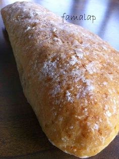 a piece of bread sitting on top of a wooden table covered in powdered sugar