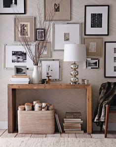 a wooden table topped with lots of books and pictures next to a lamp on top of a hard wood floor