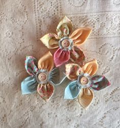 three fabric flower hair clips on a lace tablecloth