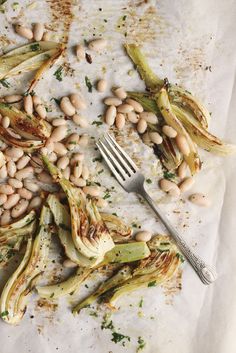 some beans and fennels are on a sheet of paper next to a fork