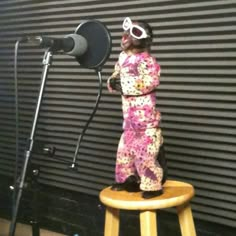 a statue of a child wearing sunglasses standing on a stool in front of a microphone