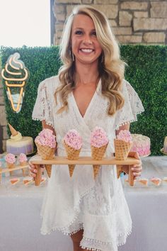 a woman is holding an ice cream tray with cupcakes on it