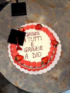 a cake that has been decorated with strawberries and writing on the top is sitting on a table