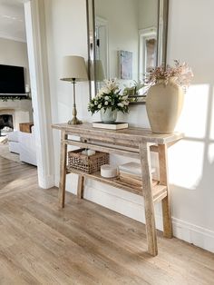 a wooden table sitting in front of a mirror on top of a hard wood floor