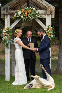 a bride and groom exchanging vows at their wedding ceremony with the dog laying on the ground