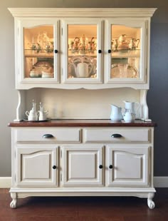 a white china cabinet with glass doors and drawers