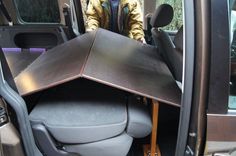 a man standing in the back seat of a vehicle with a table on it's side