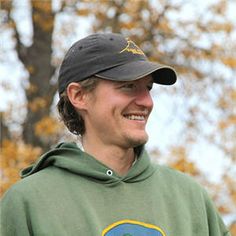 a man in a green hoodie is holding a frisbee and smiling at the camera