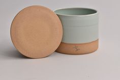 a white and blue cup with a brown lid sitting next to a small round container